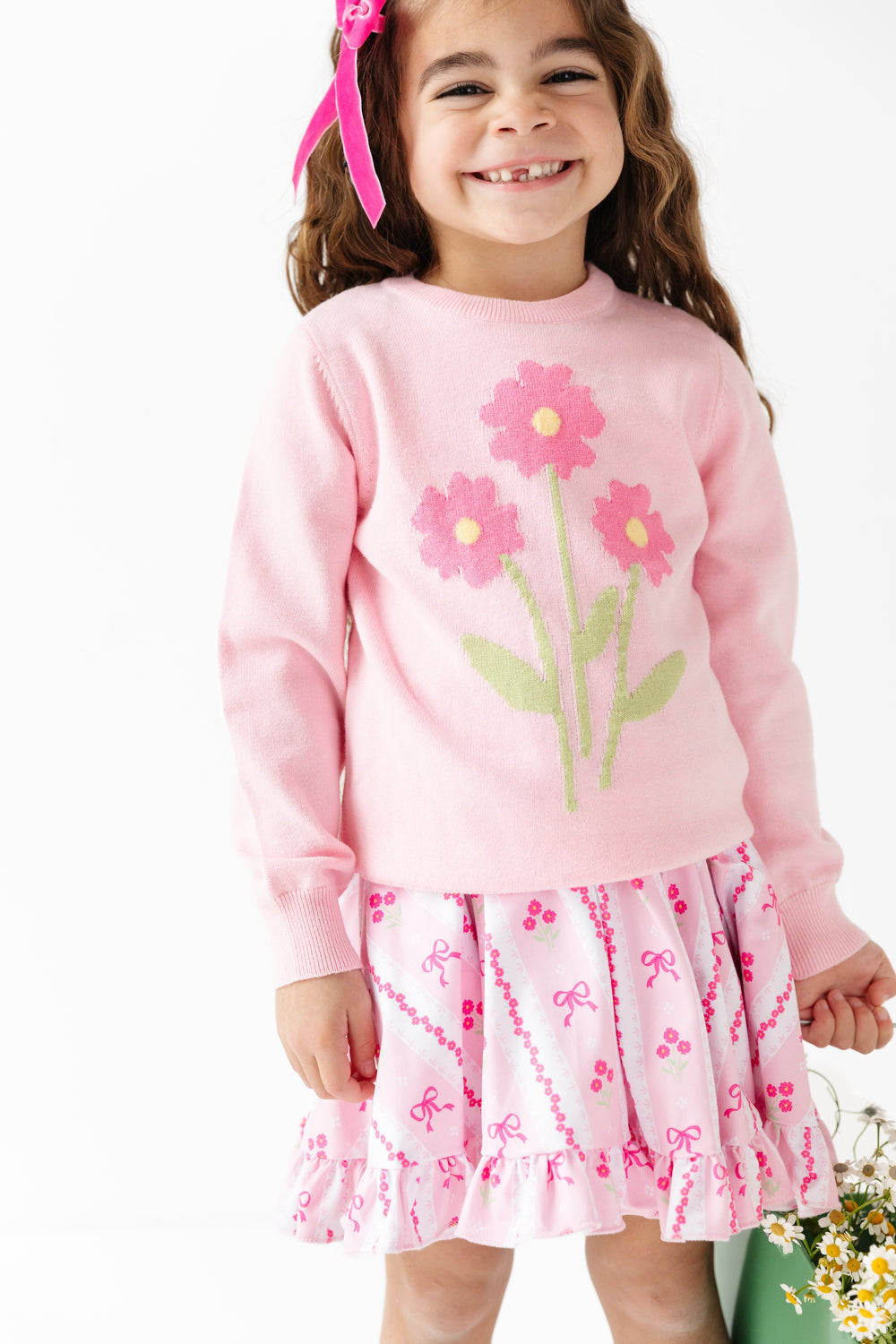 girl in twirl dress with pink bows and flower wallpaper print and matching pink flower pullover sweater