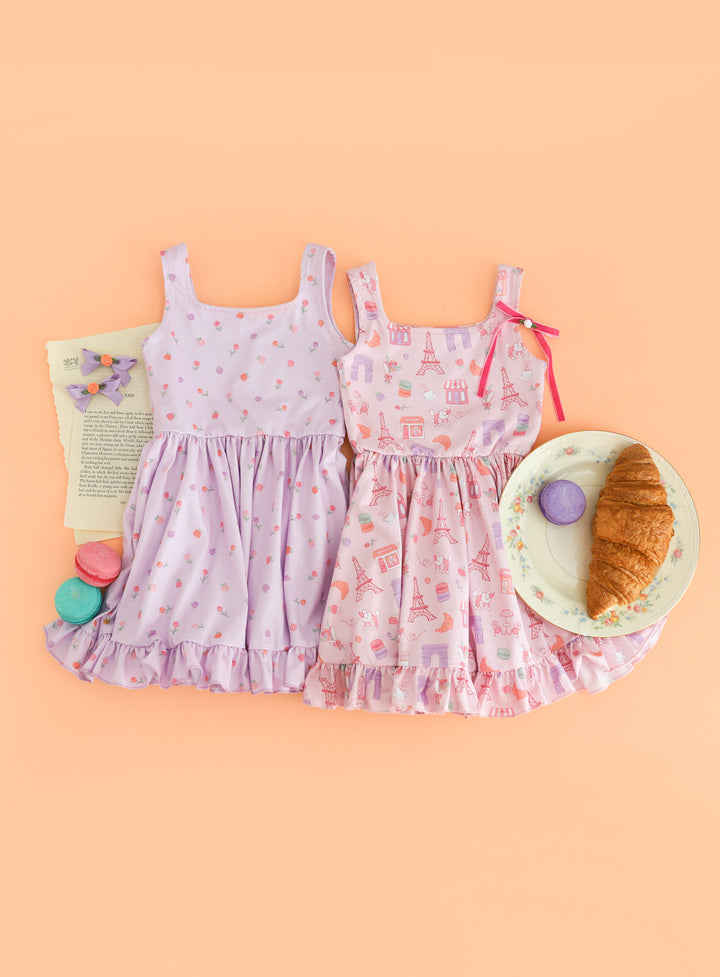 flat lay of two Paris inspired summer twirl dresses styled with rosette bows, macaroons and croissants 