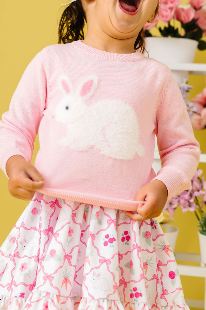 closeup of little girl in pastel pink cotton knit sweater with white fluffy Easter bunny design paired with pink and white bunny and bow print twirl dress