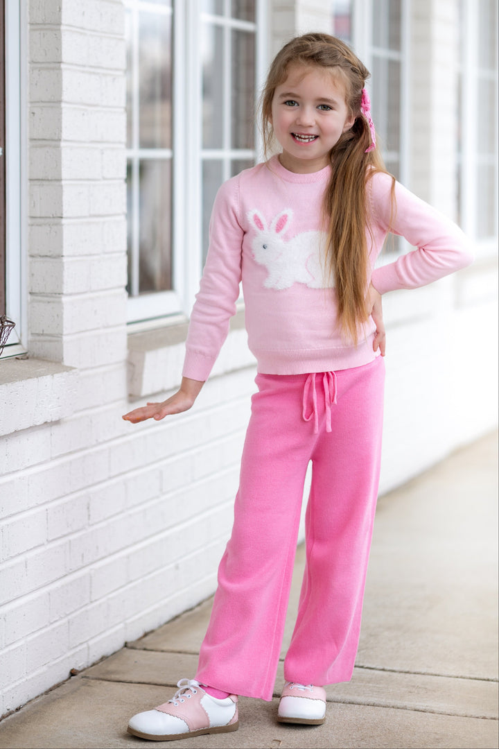 little girl posing in light pink knit sweater with fluffy white bunny design paired with medium pink sweater pants and saddle shoes