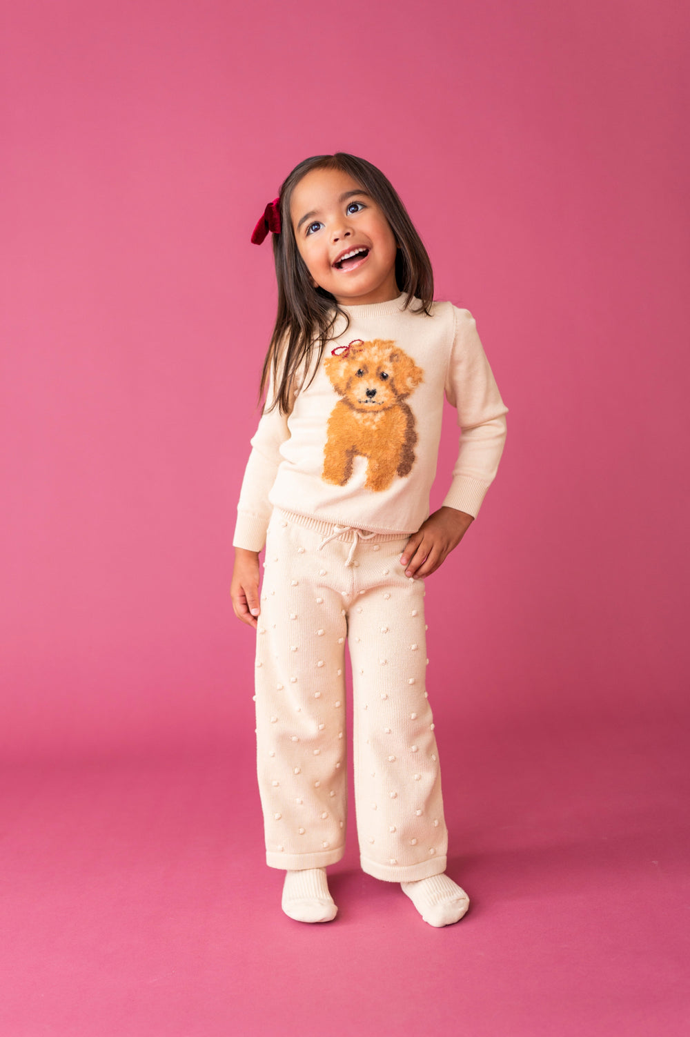 young girl in cream sweater set with fluffy yarn puppy design and 3D bubble dots on pants