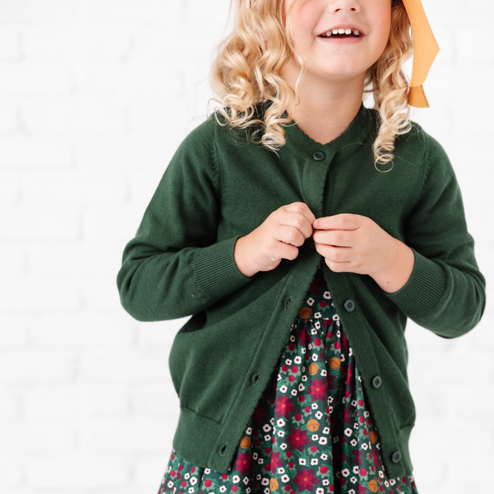 girl buttoning forest cardigan sweater