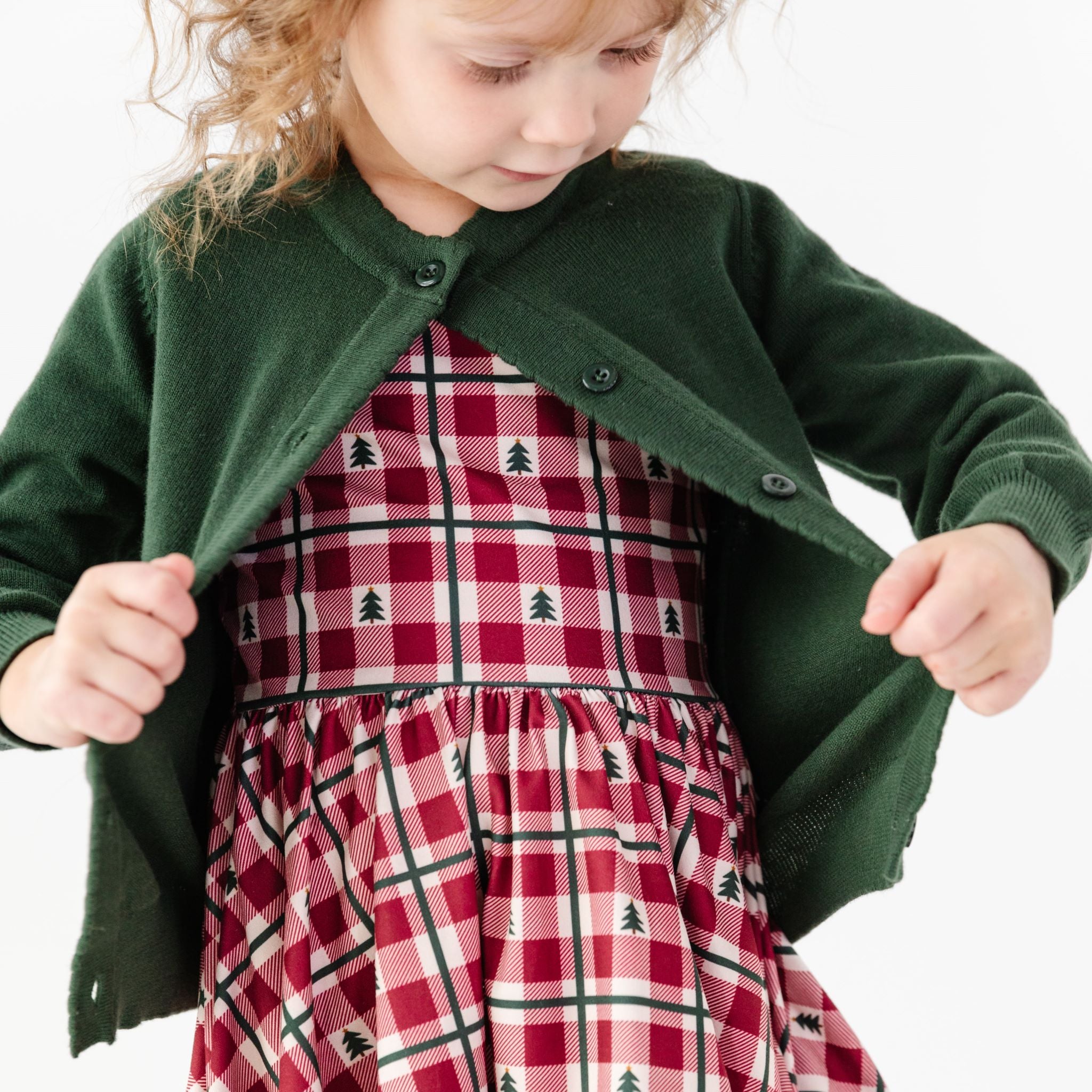 Little girl in forest green button up cardigan with matching Christmas gingham tree dress