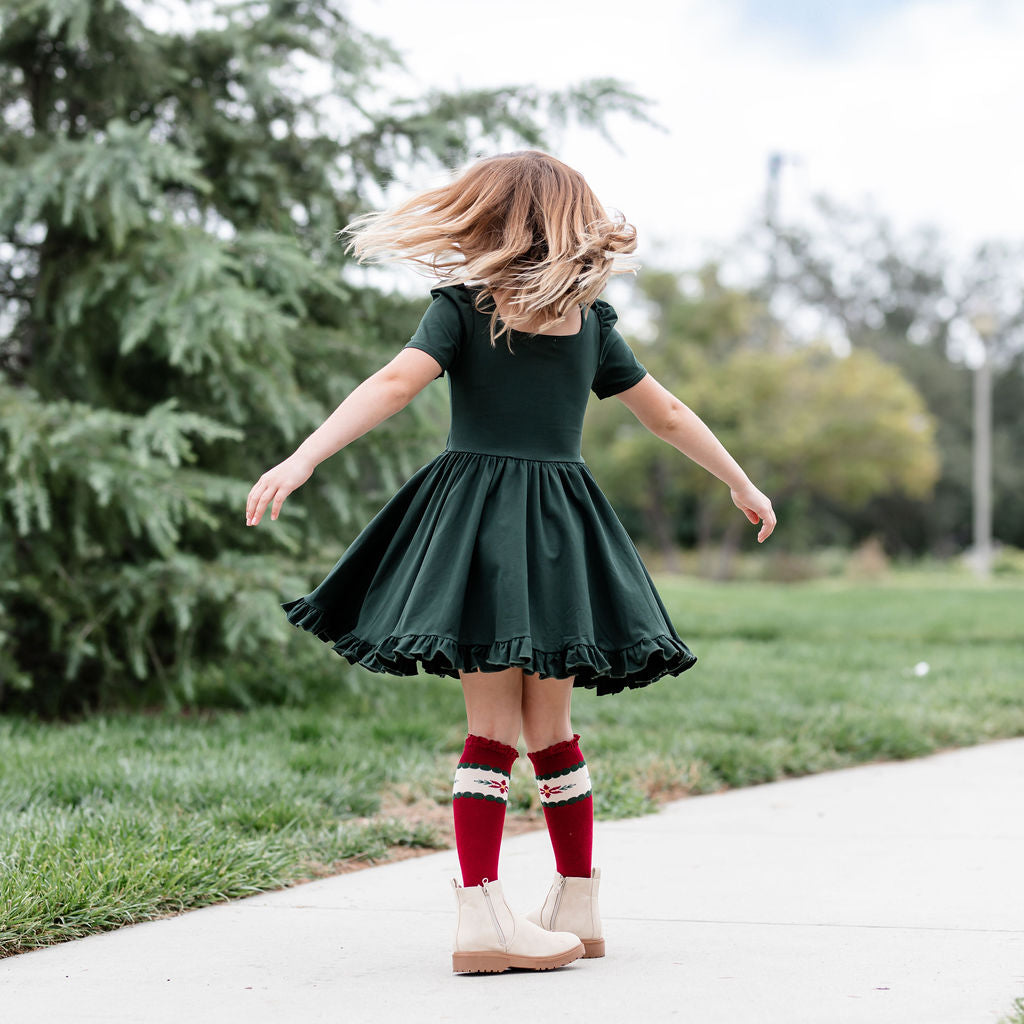 girl twirling in forest green dress with matching poinsettia socks