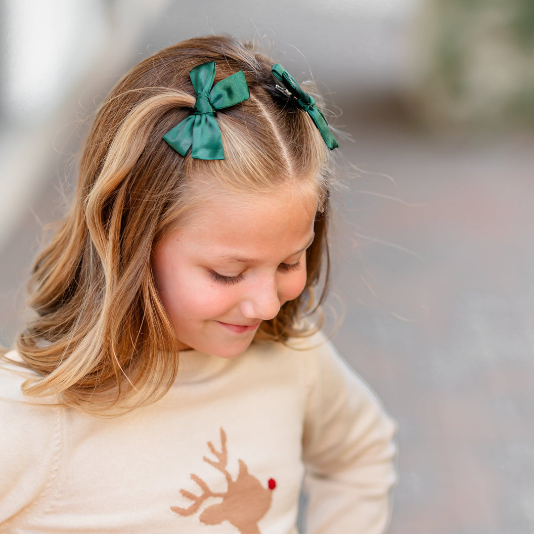 girl in reindeer knit sweater with green satin holiday pigtail bows 