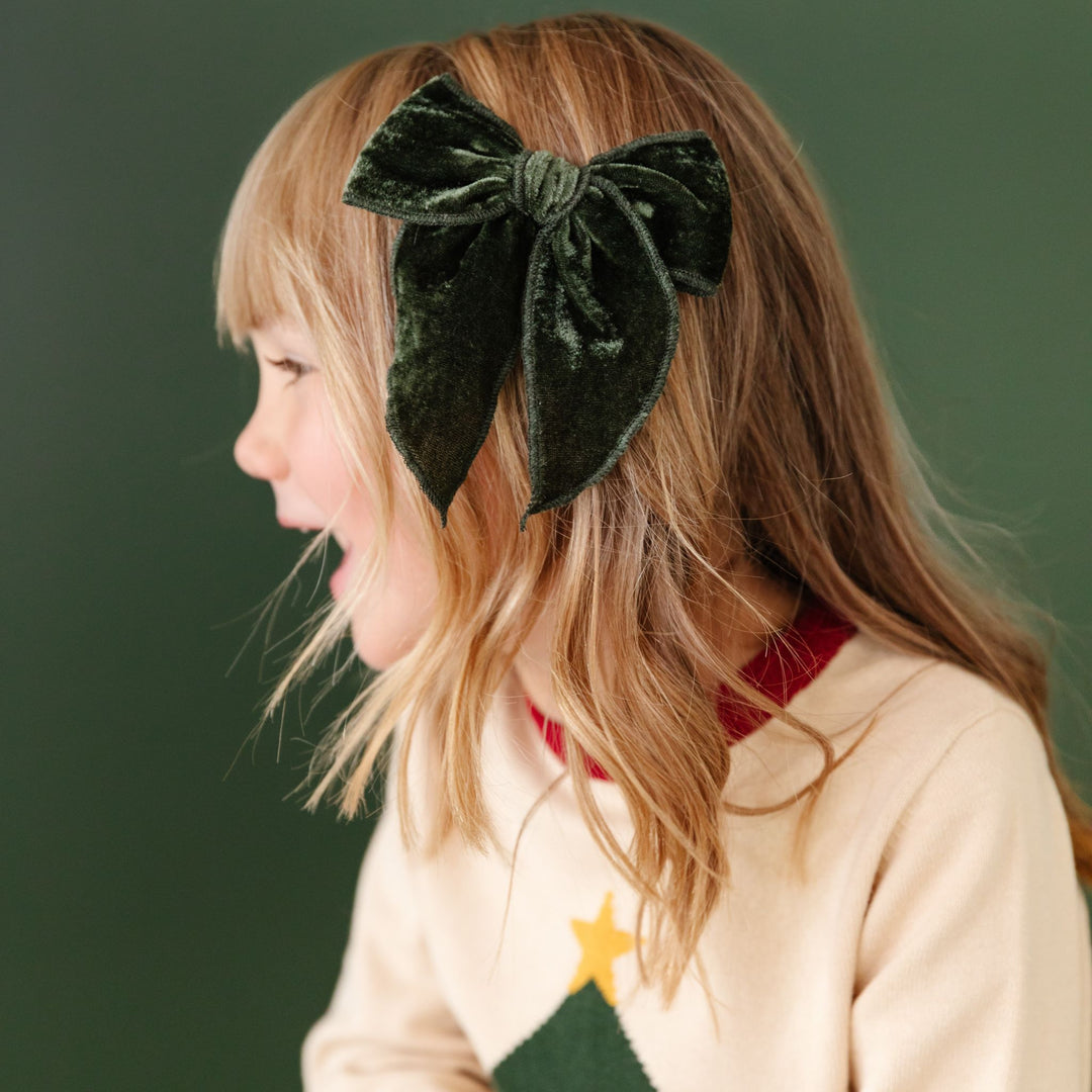 little girl in Christmas tree farm sweater with matching green velvet hairbow