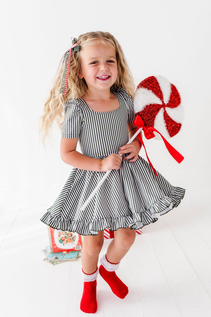 girl twirling in green and white striped chritmas dress