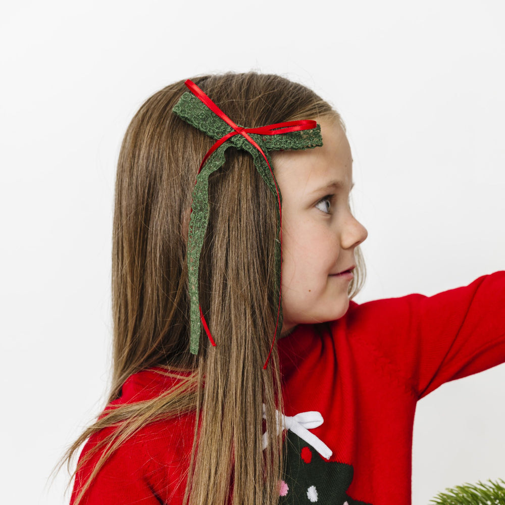 little girl in bright red Christmas tree sweater with forest green lace and red ribbon long tail bow on clip
