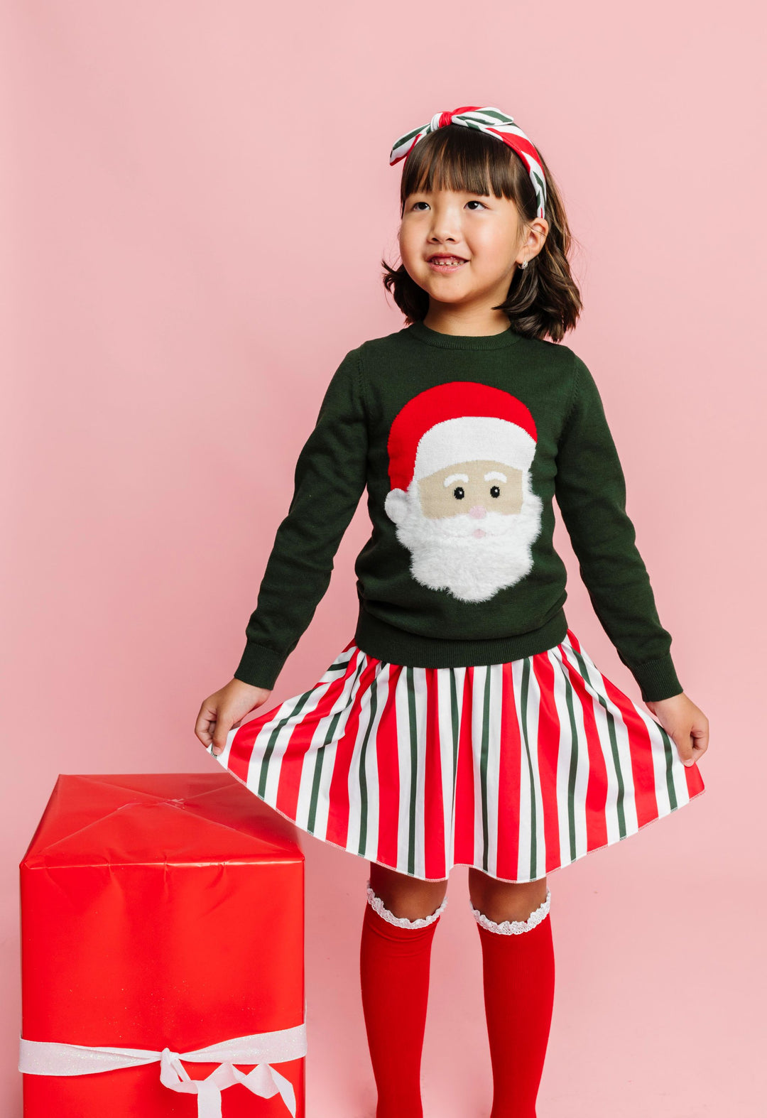 little girl in forest green pullover sweater with fluffy Santa paired with candy cane striped skirt and matching headband