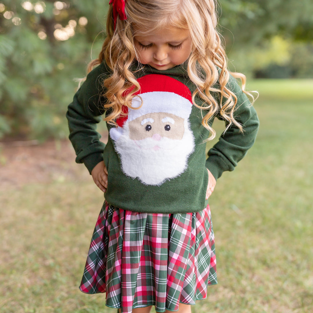 little girl in green Santa sweater with matching plaid Christmas skirt
