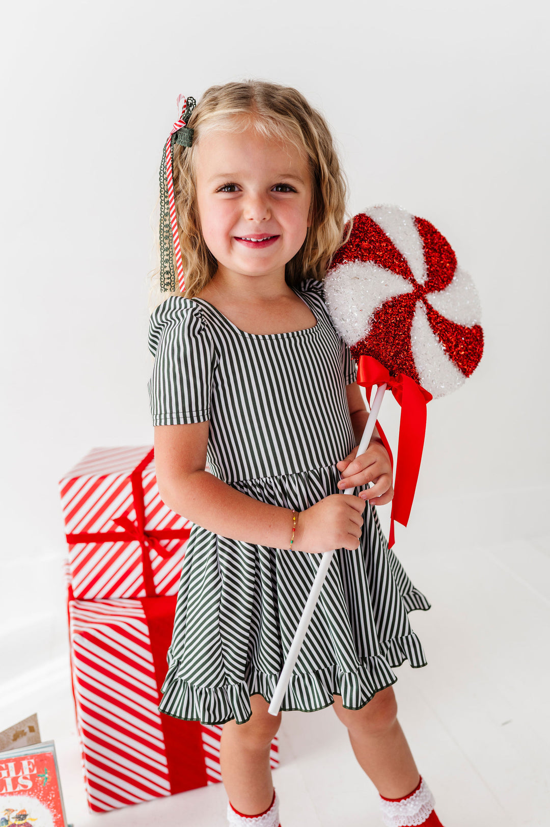 girl wearing green and white candy stripe twirl dress for christmas