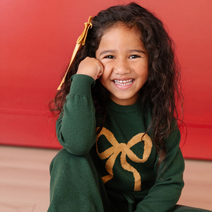 little girl wearing matching sweater set with big bow