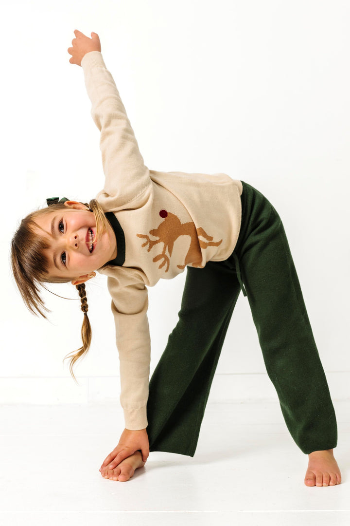 child posing in forest green knit sweater with matching cream reindeer sweater for Christmas
