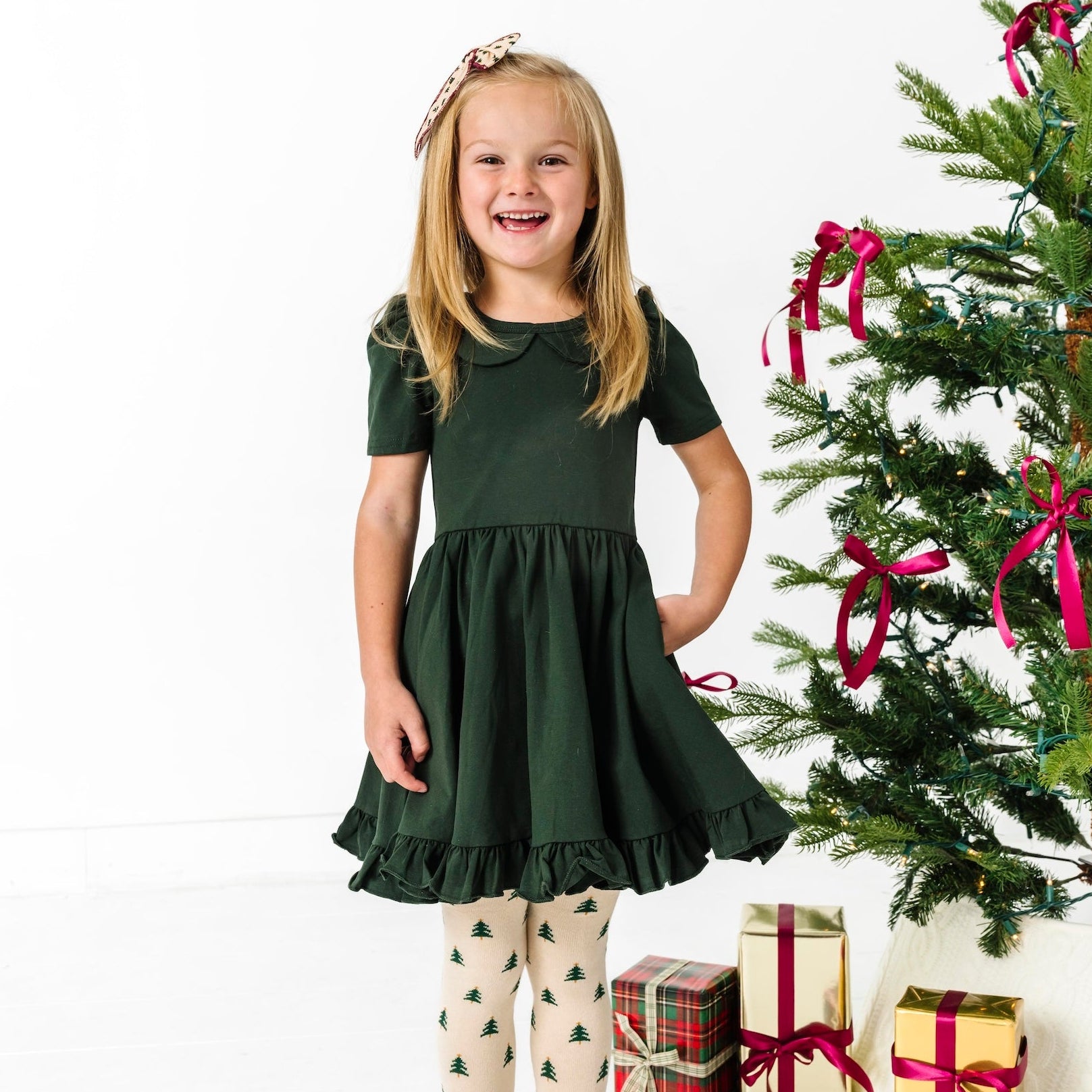 girl wearing forest green peter pan collar dress with matching christmas tree tights