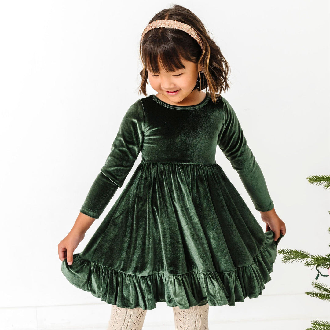 little girl in forest green long sleeve twirl dress paired with cream open knit tights and sparkly gold headband for winter