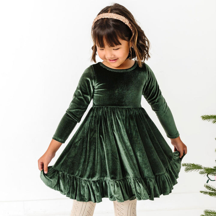 little girl in forest green long sleeve twirl dress paired with cream open knit tights and sparkly gold headband for winter