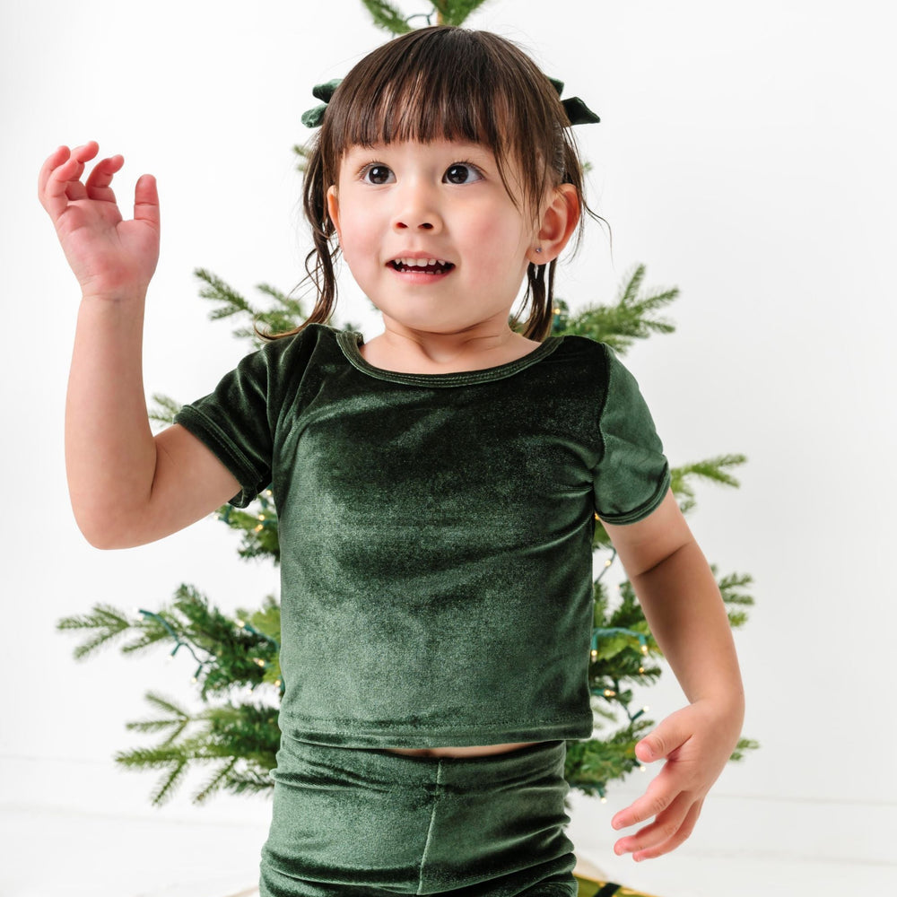 little girl in front of Christmas tree in forest green velvet fitted top
