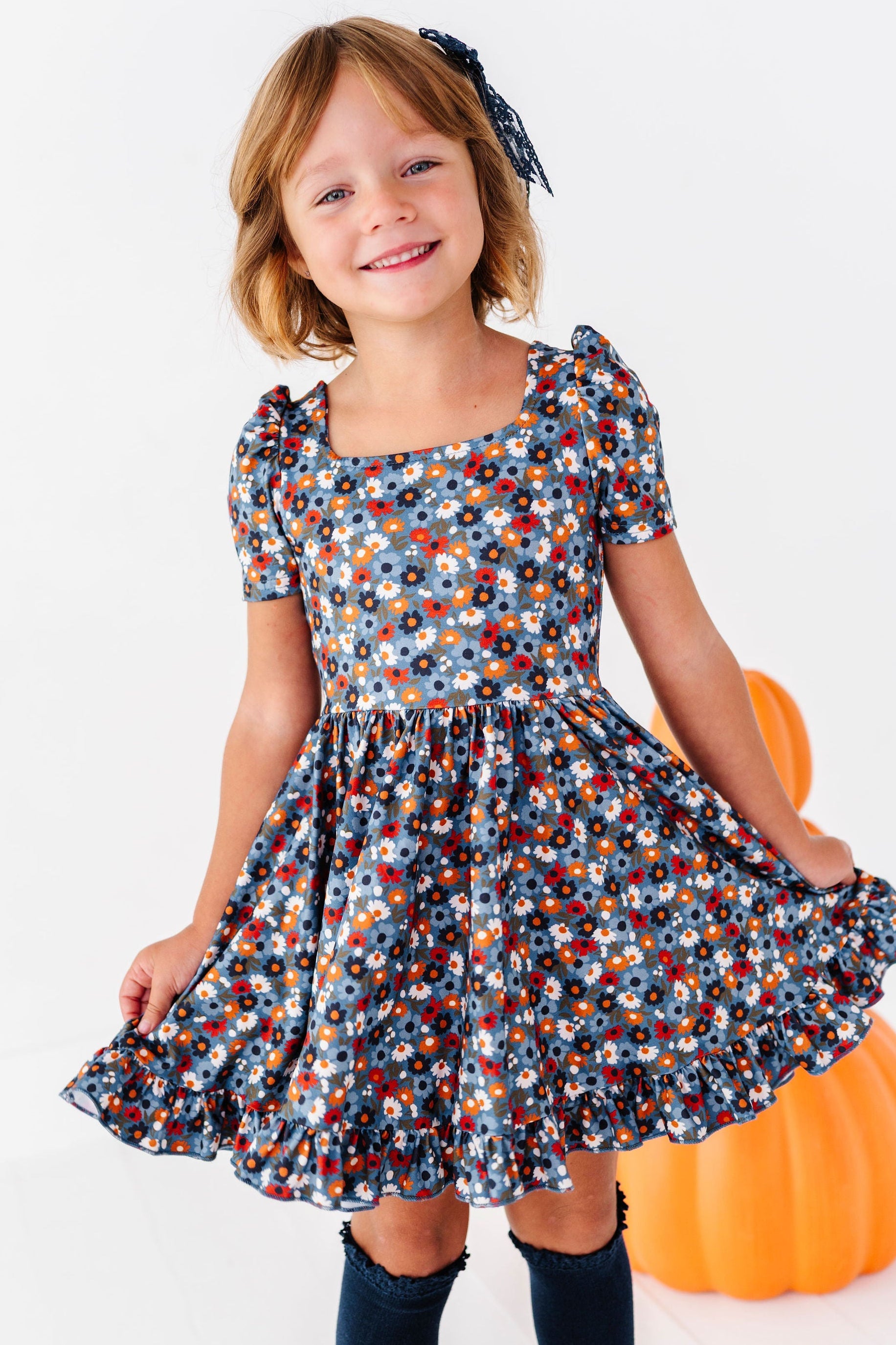 girl wearing blue floral fall twirl dress with navy knee high socks
