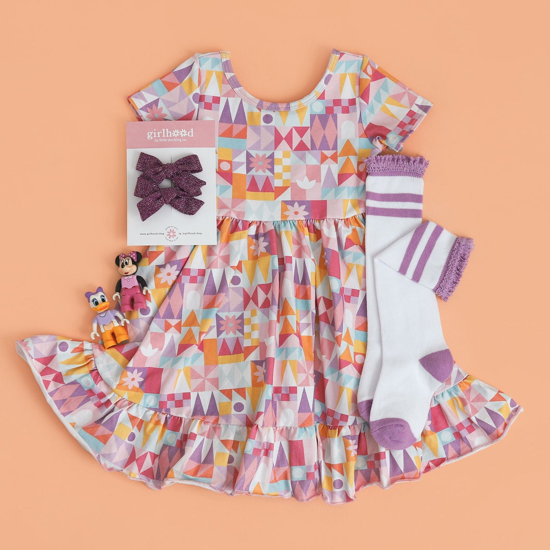 geometric pattern disney inspired dress for little girls paired with white and purple striped knee socks