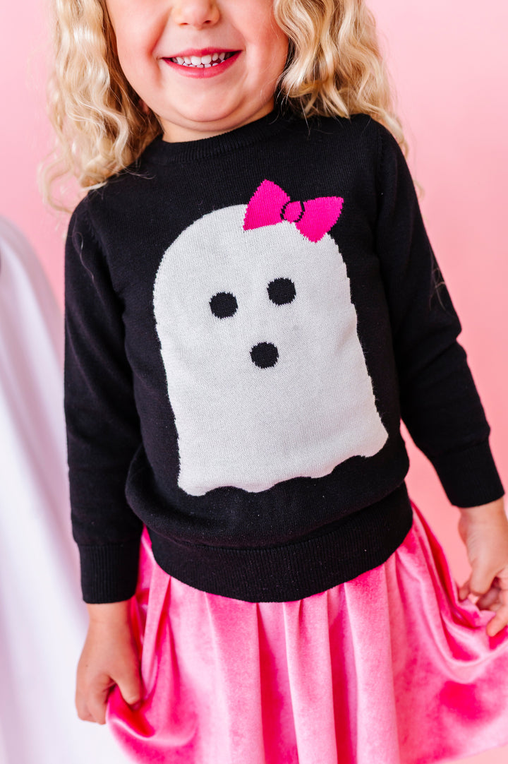 close up of little girl in black knit sweater with white ghost wearing pink bow design on the front paired with pink velvet skort for Halloween
