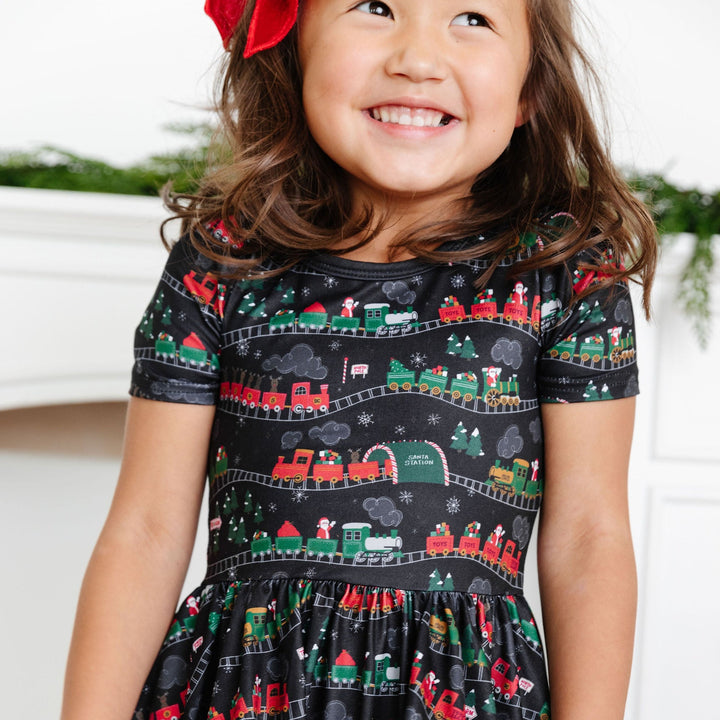little girl wearing black dress with christmas trains