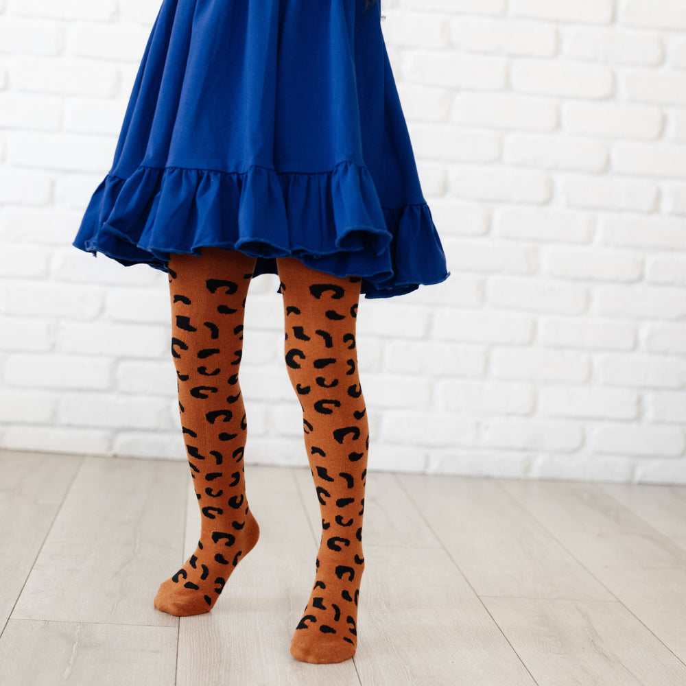 little girl standing on tip toes in cobalt blue twirl dress and leopard print tights