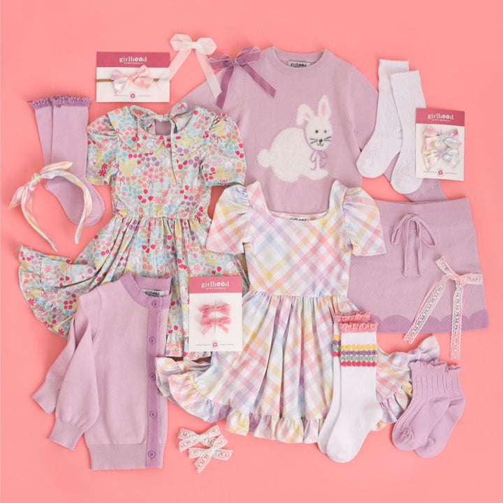 flat lay of girls' Easter outfits in coordinating pastels to pair with purple sweaters and socks