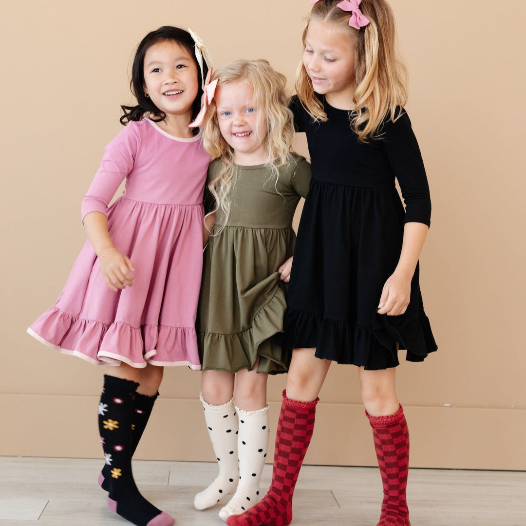 little girls wearing fall twirl dresses with patterned knee high socks