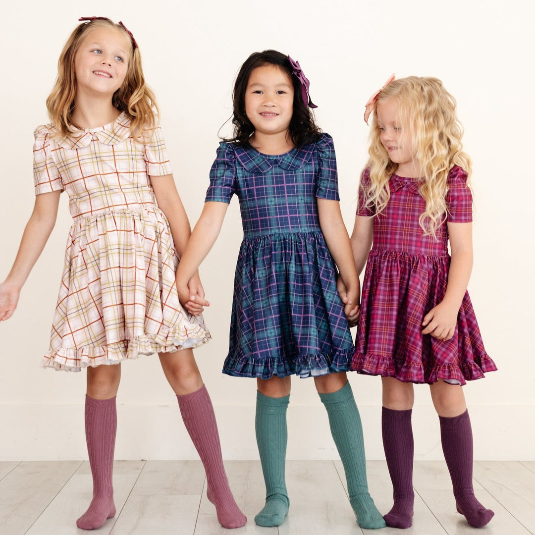 little girls wearing plaid twirl dresses with jewel tone knee high socks