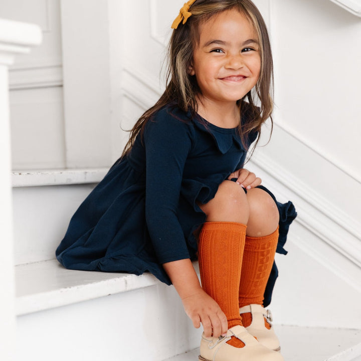 little girl wearing pumpkin orange knee high socks with navy dress
