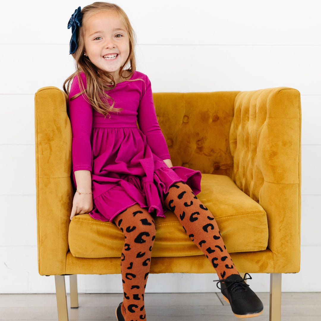 little girl sitting wearing magenta pink twirl dress and leopard print tights