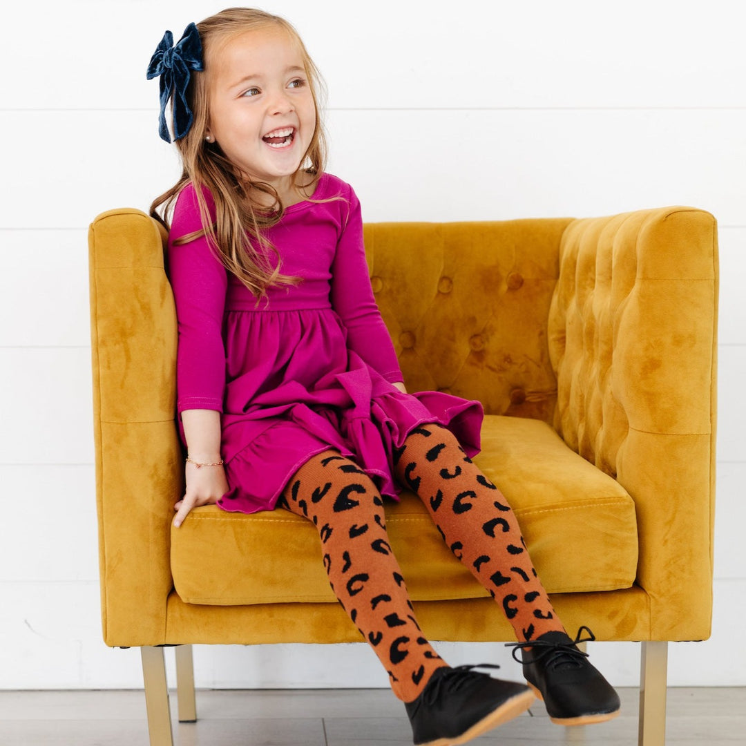little girl wearing magenta pink party dress with leopard print knit tights
