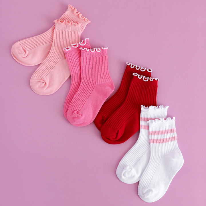 flatlay of ribbed midi socks with lettuce trim in light pink, bright pink, red and white with pink stripes for valentines day