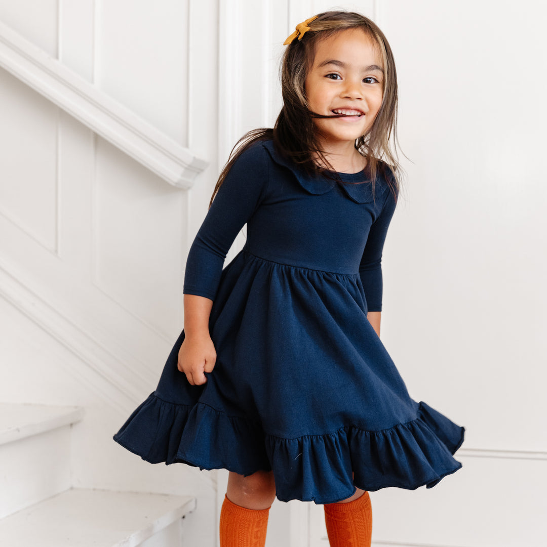 little girl twirling in navy long sleeve twirl dress with pockets