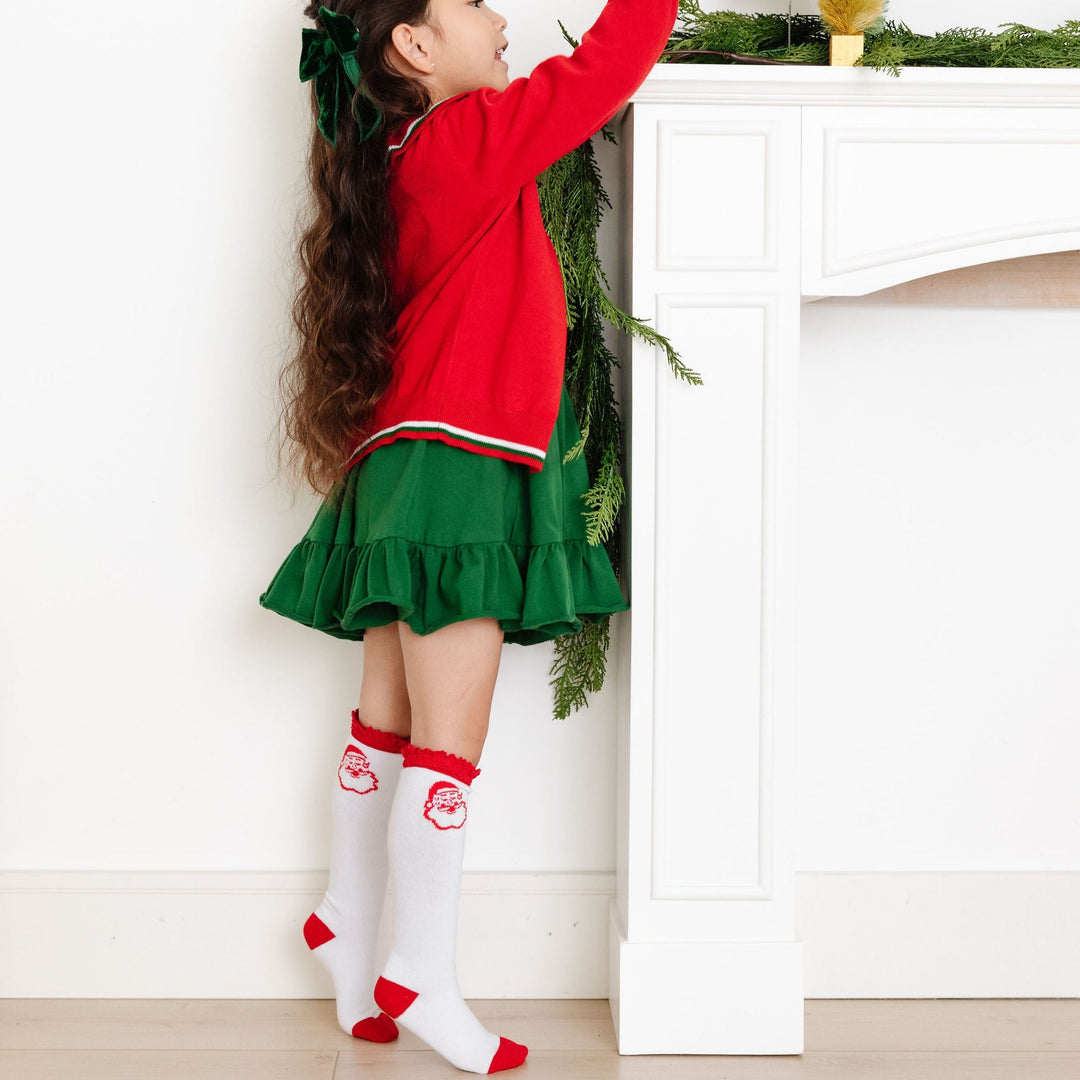 little girl wearing santa face knee high socks with christmas dress and sweater