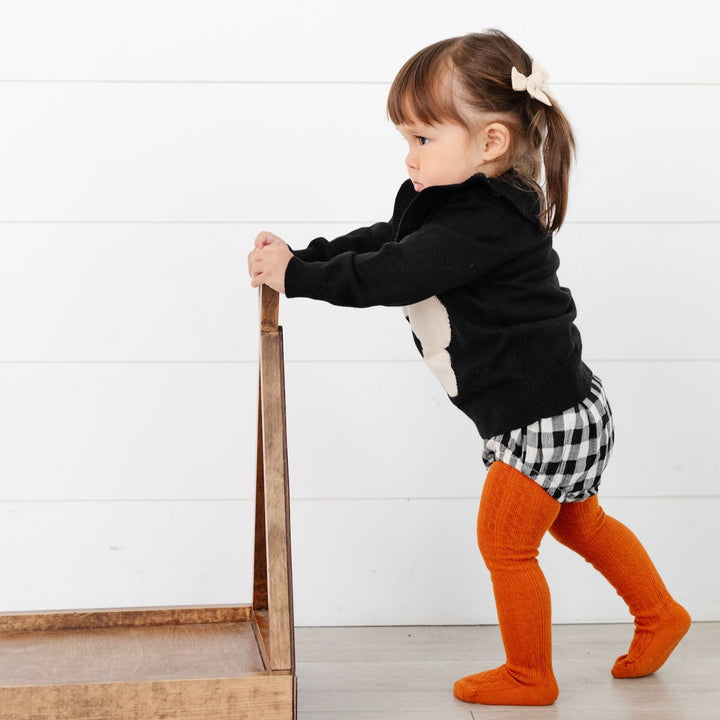 toddler girl wearing pumpkin spice orange cable knit tights with bloomers and sweater