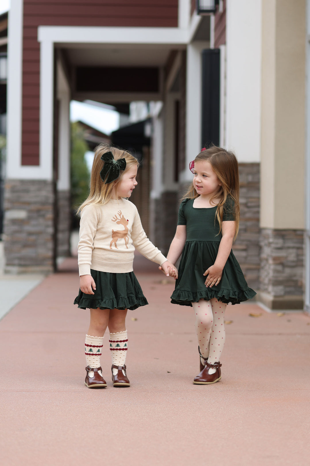 little girls wearing forest green christmas dresses with matching socks, tights, reindeer sweater and velvet hair bow