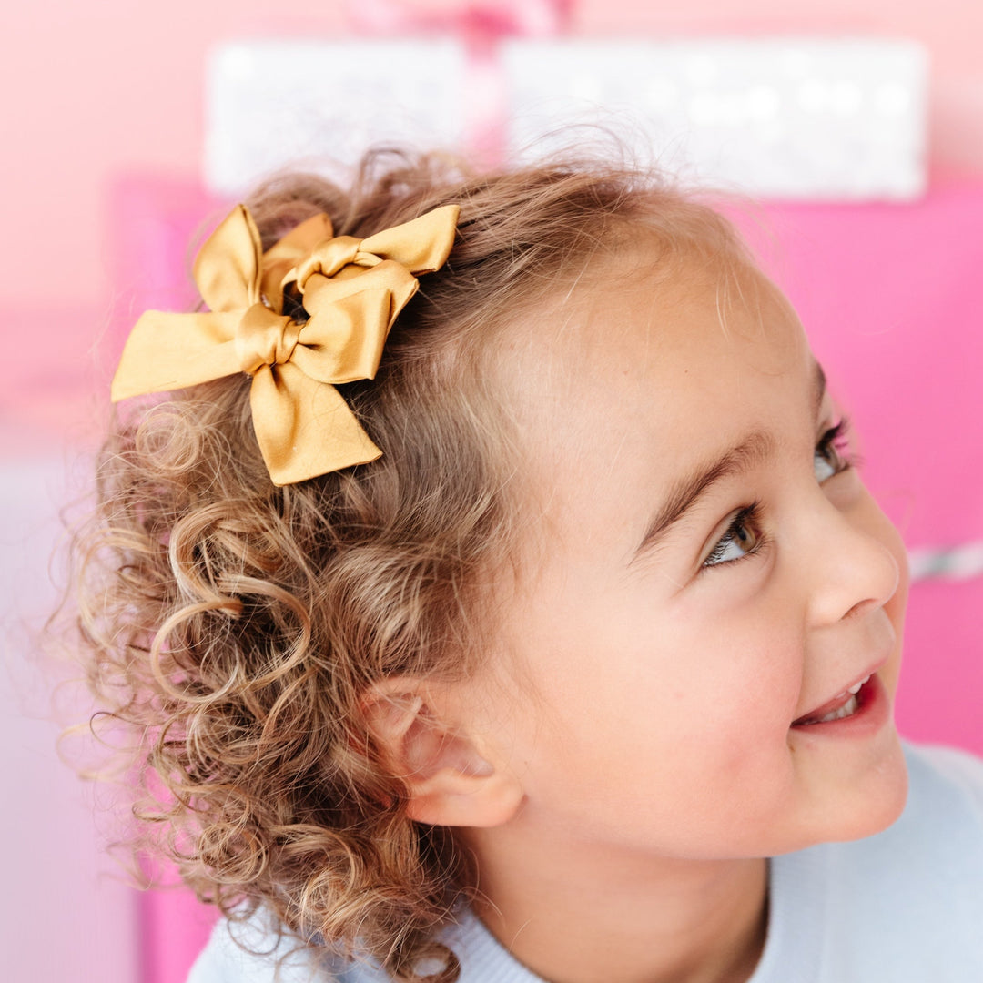 girl in gold satin pigtail bow styled with pink Christmas