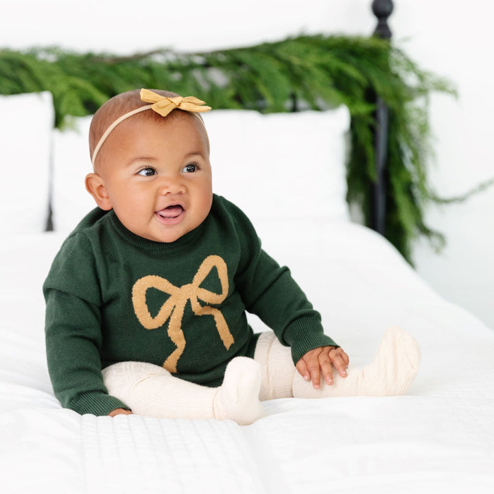 baby girl in matching christmas sweater set with gold bow