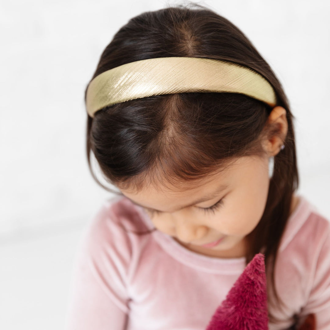 little girl in shiny gold Christmas headband and pink velvet dress