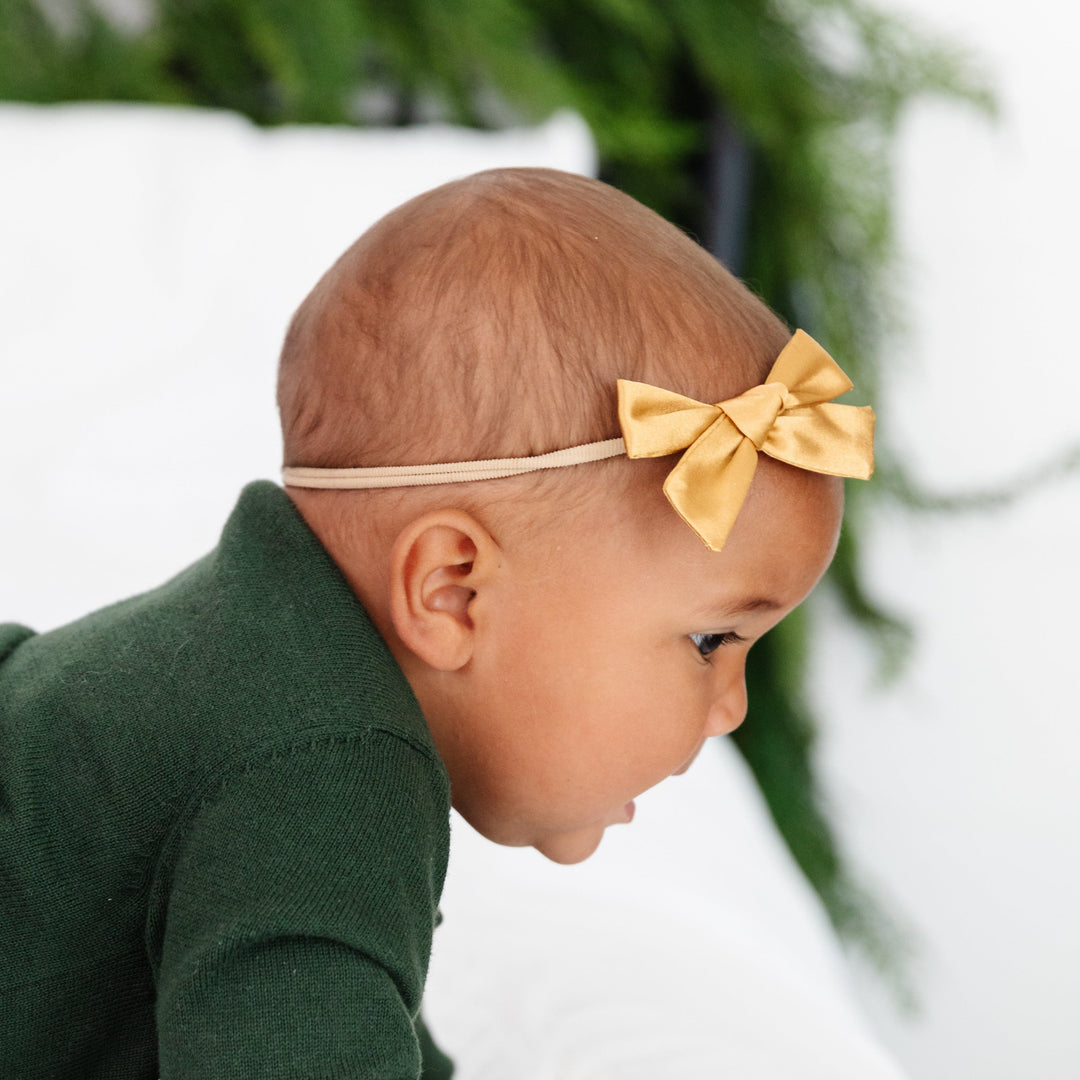 baby girl in gold satin bow headband on nylon band and forest green knit sweater set