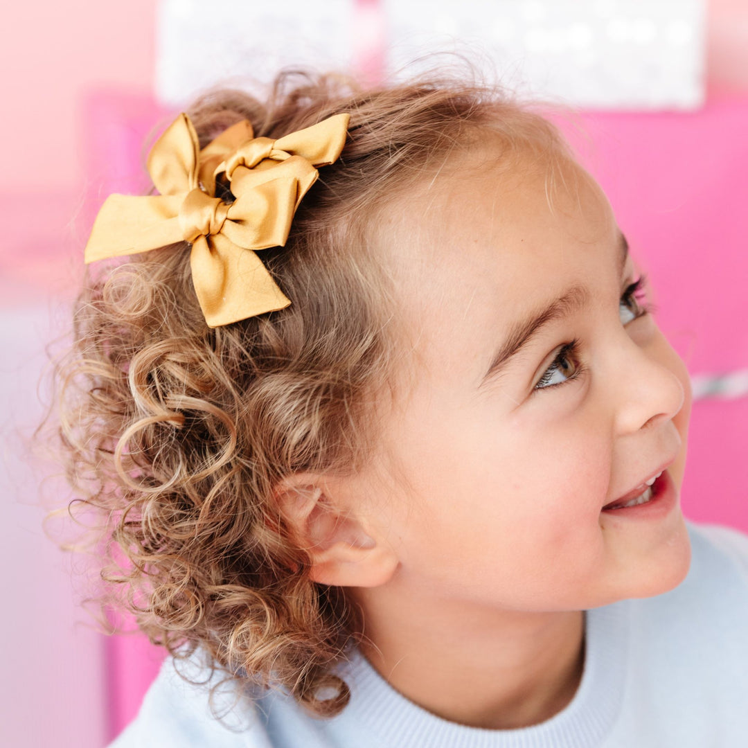 little girl in set of gold satin pigtail bows