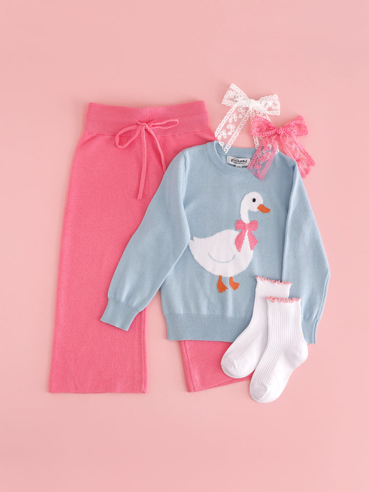 flat lay of girls' Easter goose sweater set with blue cotton knit goose sweater paired with matching pink sweater pants, white and pink lace bows and white ribbed midi socks with pink lettuce trim