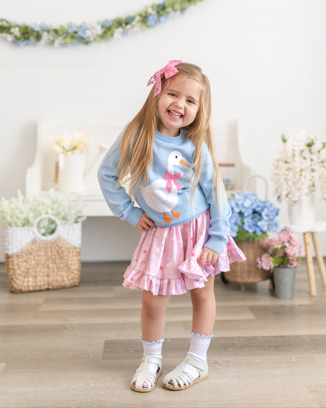 little girl in blue goose sweater with matching pastel pink goose print twirl dress and matching accessories for Easter