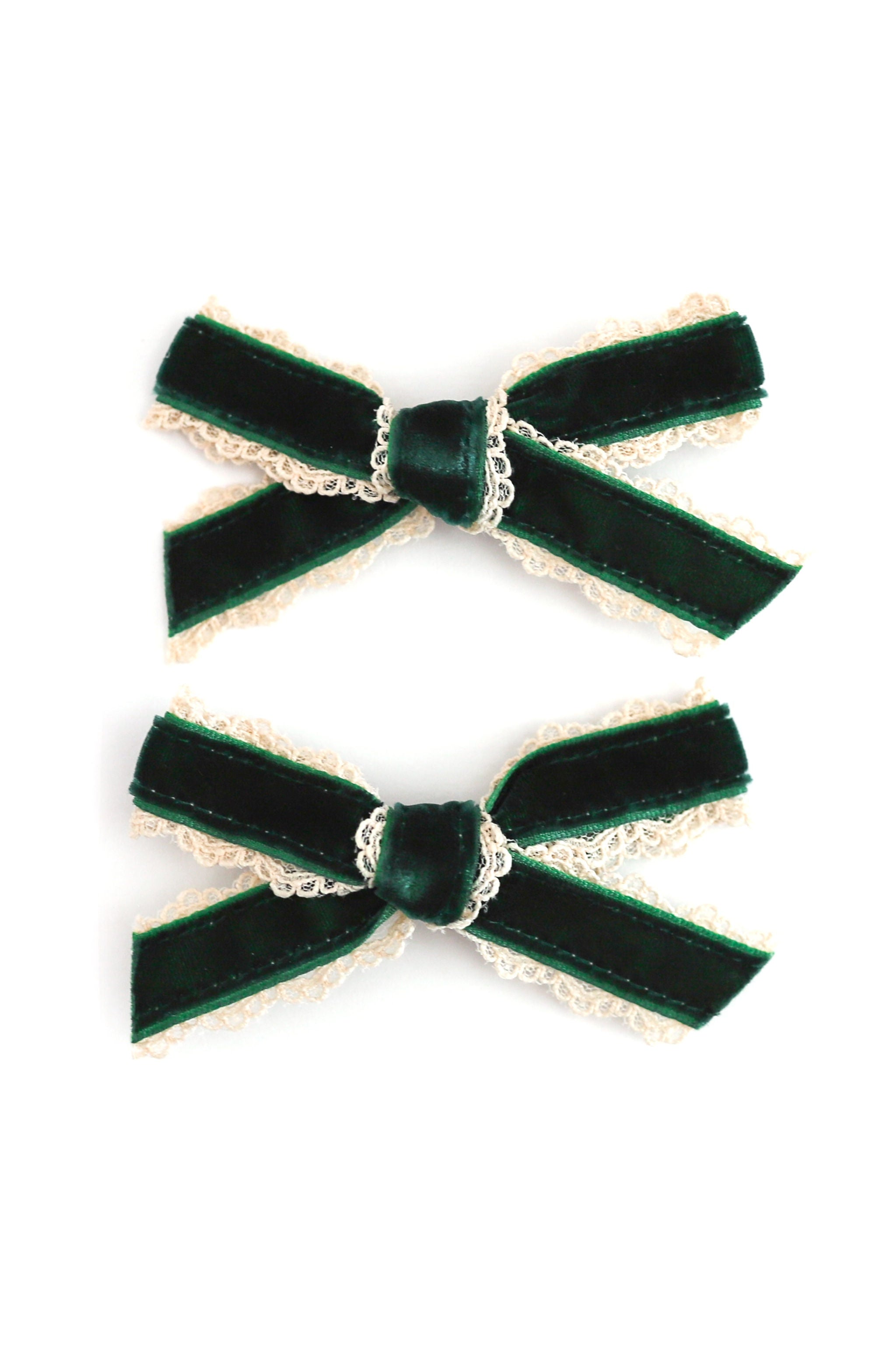 Two dark green velvet hair bows with cream lace trim, arranged vertically on a plain white background.