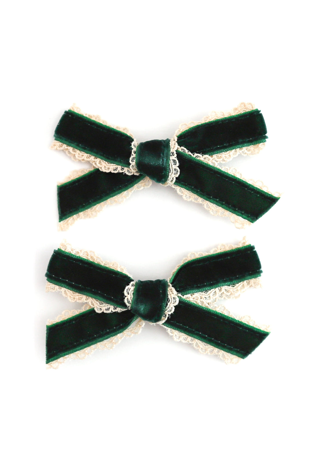 Two dark green velvet hair bows with cream lace trim, arranged vertically on a plain white background.
