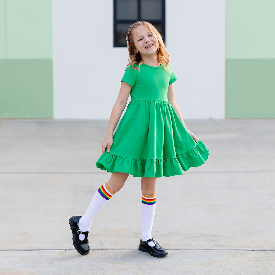 little girl in irish green solid dress and rainbow stripe knee high socks