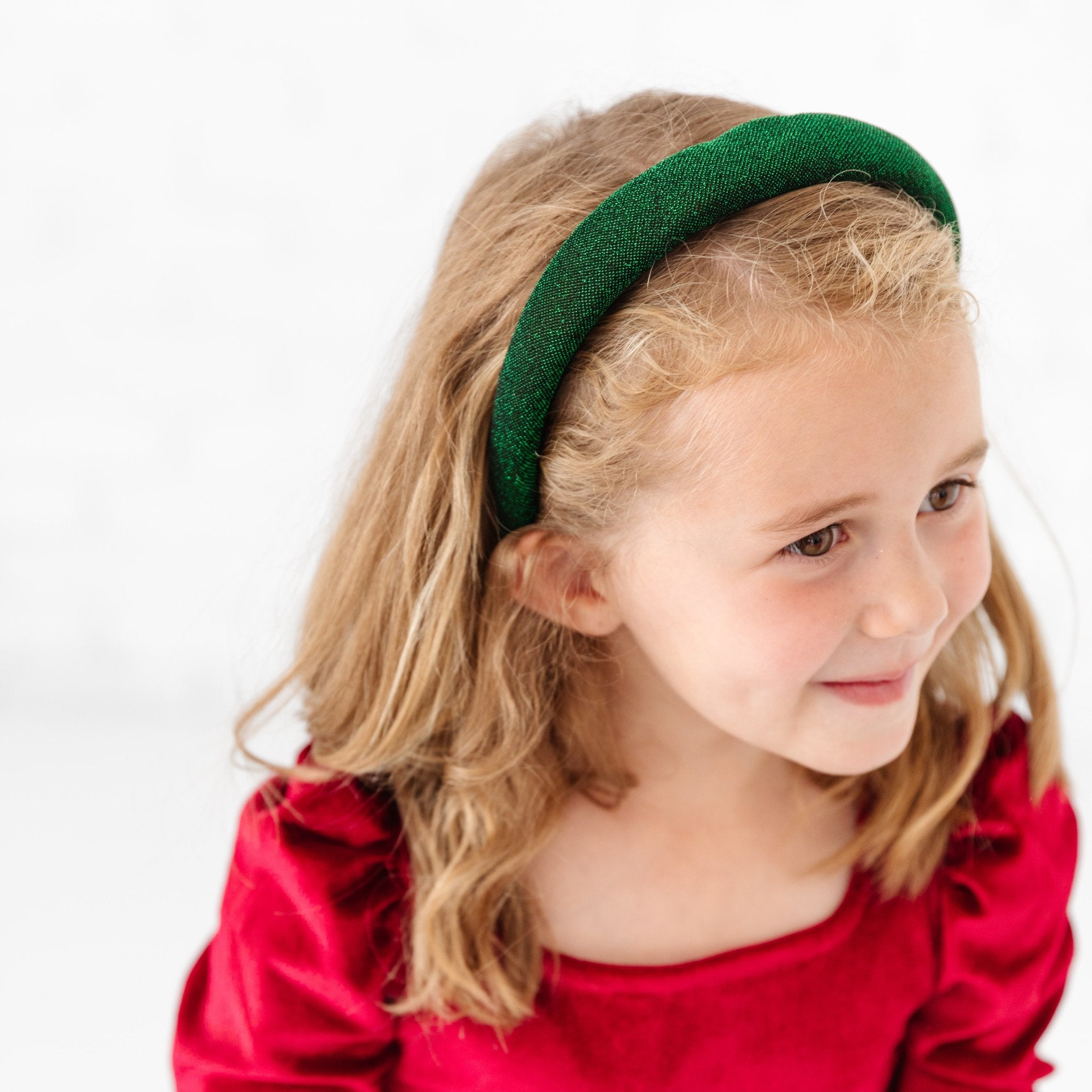 girl in red velvet Christmas dress and padded green sparkle headband