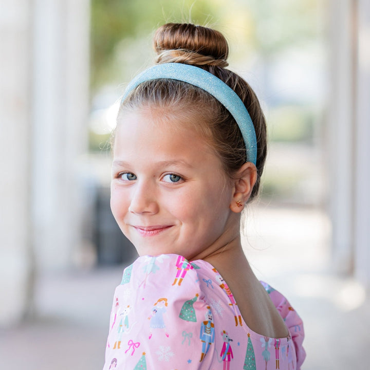 girl in light blue sparkle padded headband and pink nutcracker holiday dress