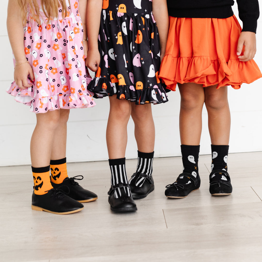 little girls wearing halloween midi socks with pumpkins, black and white stripes and ghosts